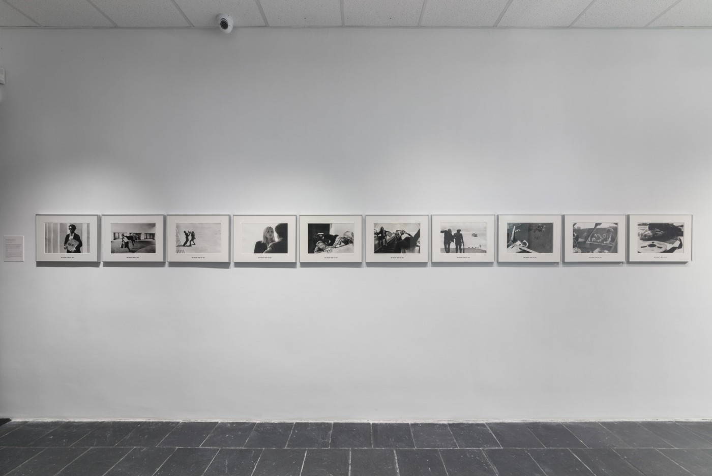 Installation view of ten black and white photographs by David Lamelas in a linear arrangement on a white wall.